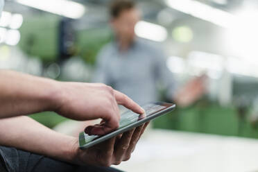 Businessman working on digital tablet with male colleague in factory - DIGF13851