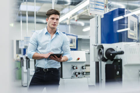 Junger Geschäftsmann mit digitalem Tablet bei der Arbeit in der Industrie - DIGF13869