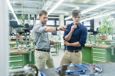 Male colleagues having meeting seen through glass while working in factory - DIGF13900