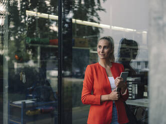 Selbstbewusste Geschäftsfrau mit digitalem Tablet vor dem Büro - GUSF04914