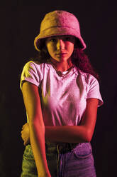 Nahaufnahme eines selbstbewussten Teenagers mit Hut, der vor einem schwarzen Hintergrund posiert - JRVF00071