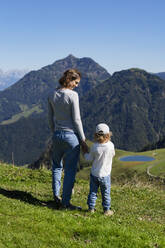 Mutter wandert mit kleiner Tochter in den frühlingshaften Bergen - DIGF13968
