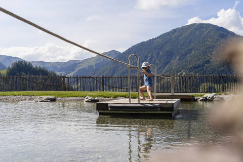 Little girl crossing lake on small wooden raft stock photo