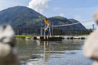 Mother and little daughter crossing lake on small wooden raft - DIGF13977