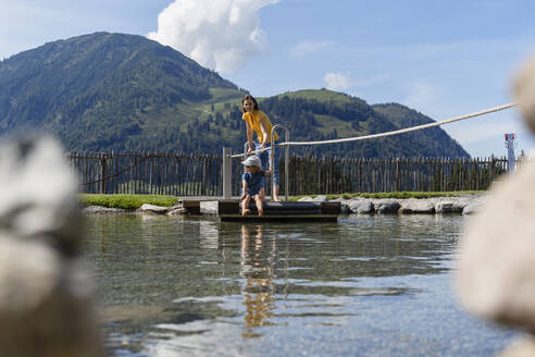 Mutter und kleine Tochter überqueren den See auf einem kleinen Holzfloß - DIGF13977