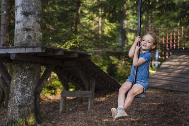 Little girl riding forest zip line - DIGF13986