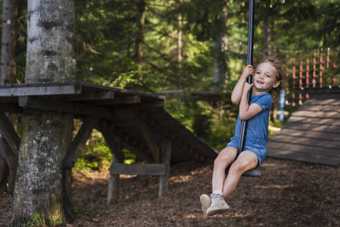 Kleines Mädchen reitet auf einer Seilrutsche im Wald - DIGF13986