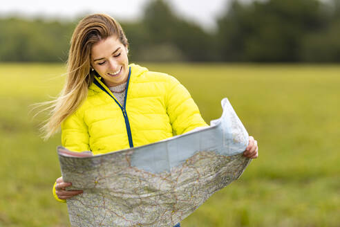 Portrait of young beautiful woman smiling while standing outdoors with map in hands - GGGF00630