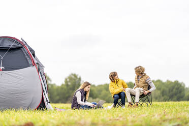 Three siblings camping on grass - GGGF00640