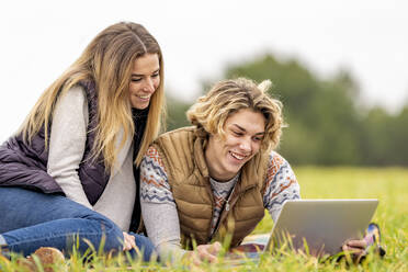 Bruder und Schwester liegen zusammen im Gras mit digitalem Tablet - GGGF00642