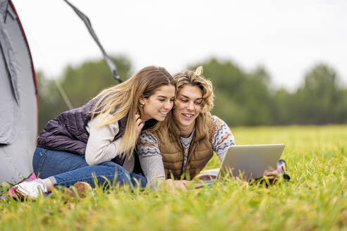 Bruder und Schwester liegen zusammen im Gras mit digitalem Tablet - GGGF00643