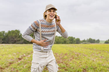 Porträt eines jungen Mannes, der auf einer Wiese mit seinem Smartphone telefoniert - GGGF00650