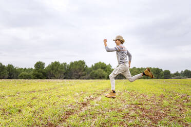 Junger Mann springt und posiert in der Luft auf einer Wiese - GGGF00651