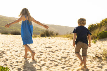 Bruder und Schwester spielen, während sie auf Sand laufen - SBOF02312