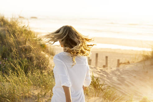 Frau läuft am Strand bei Sonnenuntergang - SBOF02324