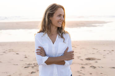 Smiling woman with looking away while standing at beach - SBOF02348