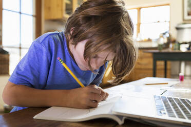 Young boy at home writing and drawing in his drawing pad - MINF15494