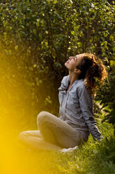 Sportswoman looking up while sitting at park - MAUF03708