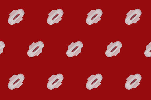 Muster von blutbefleckten Damenbinden vor rotem Hintergrund - GEMF04538
