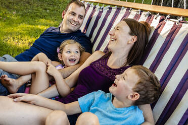 Lachende Familie beim Entspannen in der Hängematte am Wochenende - AWAF00021