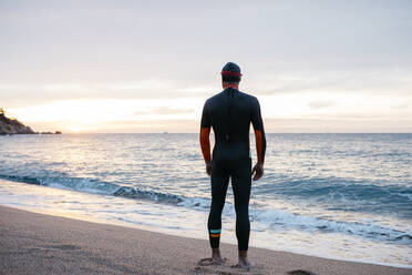 Männlicher Schwimmer bewundert das Meer bei Sonnenuntergang - JRFF04962