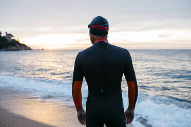 Männlicher Schwimmer bewundert das Meer bei Sonnenuntergang - JRFF04963