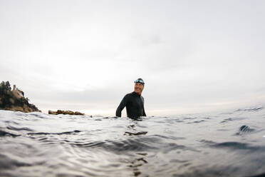 Männlicher Schwimmer steht hüfttief im Meerwasser - JRFF04988