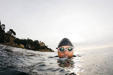 Kopf eines Mannes, der beim Schwimmen im Meer in die Kamera schaut - JRFF04998