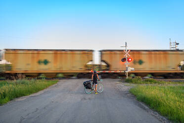 Radfahrer wartet auf einen vorbeifahrenden Zug, Ontario, Kanada - ISF24323