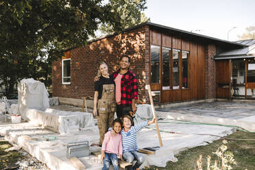 Porträt eines lächelnden Paares mit verspielten Kindern, die vor einem Haus stehen - MASF21141