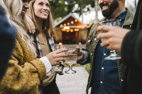 Smiling women with friends drinking while enjoying during social gathering stock photo