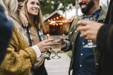 Lächelnde Frauen mit Freunden beim Trinken während eines geselligen Beisammenseins - MASF21173