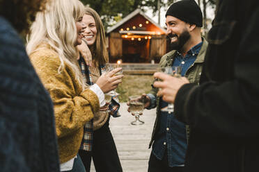 Fröhliche Frauen mit Freunden beim Trinken während eines geselligen Beisammenseins - MASF21174