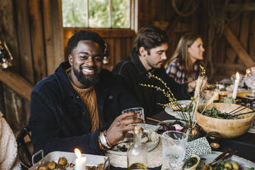 Portrait of smiling man enjoying with female and male friends during social gathering - MASF21189