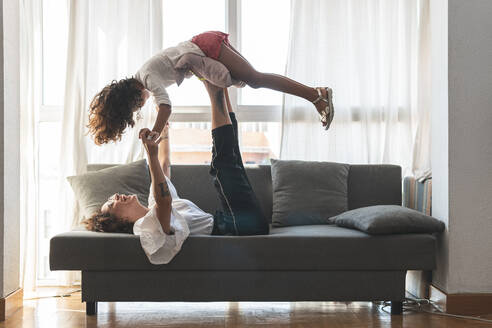 Mother and daughter playing on sofa - JAQF00120