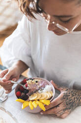 Young woman eating bowl of granola with fruits - JAQF00128