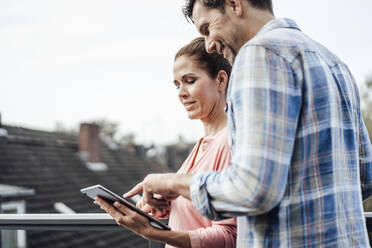 Happy mature couple using digital tablet in balcony - JOSEF02701