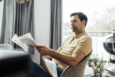 Älterer Mann liest Zeitung im Wohnzimmer zu Hause - JOSEF02728