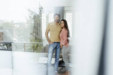Smiling mature couple seen through glass at home - JOSEF02740