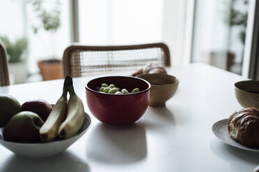 Fruits and croissant in bowl on dining table at apartment - JOSEF02769