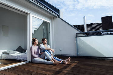 Lächelnder reifer Mann und Frau entspannen sich mit geschlossenen Augen auf dem Balkon an einem sonnigen Tag - JOSEF02832