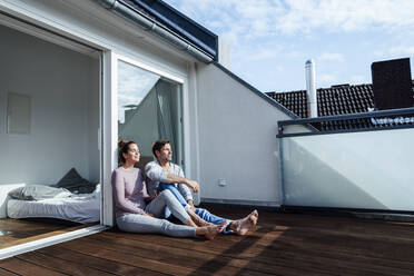 Smiling mature man and woman relaxing with eyes closed in balcony on sunny day - JOSEF02832