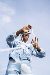 Gefangener junger Mann entfernt Seil, während er gegen den Himmel steht - AFVF08016