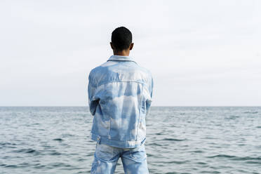 Young man wearing denim suit standing against sea - AFVF08034