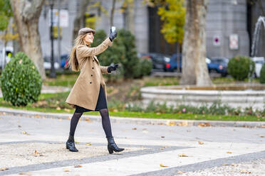 Frau macht Selfie beim Gehen auf dem Fußweg - GGGF00696