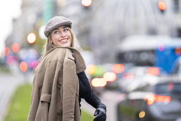 Glückliche Frau, die einen Mantel hält und auf der Straße steht - GGGF00705