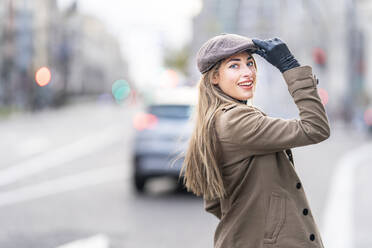 Frau hält Mütze, während sie auf der Straße steht - GGGF00709