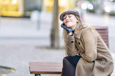Lächelnde Frau, die auf einer Bank am Fußweg sitzt und träumt - GGGF00714
