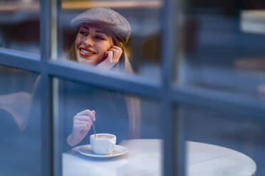 Thought woman with coffee cup looking through window of cafe - GGGF00730