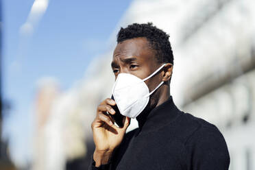 Young man talking on mobile phone while standing outdoors - PGF00335